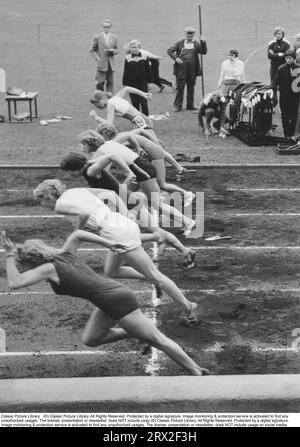 Der Beginn eines laufenden Wettbewerbs. Sechs konkurrierende Frauen werden gleich zum Startzeitpunkt gesehen und machen die ersten kraftvollen Schritte im 100-Meter-Rennen. Schweden 1957 Stockfoto