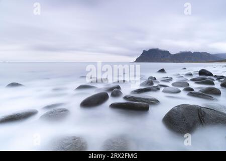 Wolken in der Dämmerung über Felsen, die vom arktischen Meer am Uttakleiv-Strand, Vestvagoy, Lofoten-Inseln, Nordland, Norwegen, Skandinavien, Europa Stockfoto