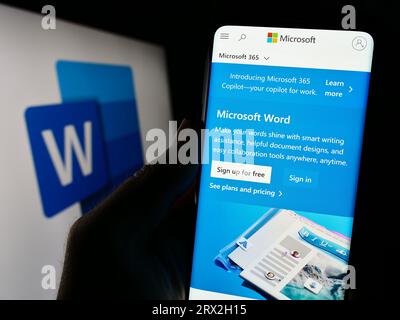 Person, die ein Mobiltelefon mit Website der Textverarbeitungssoftware Microsoft Word auf dem Bildschirm vor dem Logo hält. Konzentrieren Sie sich auf die Mitte der Telefonanzeige. Stockfoto