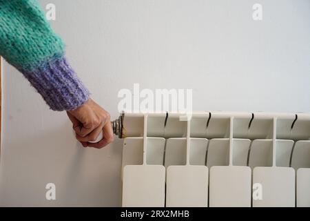 Frau passt die Temperatur am Heizkörper an. Erhöhung des Erdgaspreises. Teure, vertraute Wirtschaft Stockfoto