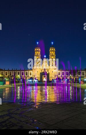 Zapopan Basilika, Guadalajara, Mexiko, beleuchtet von Scheinwerfern bei Nacht und von farbigen Wasserfontänen im Vordergrund. Stockfoto