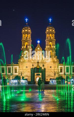 Zapopan Basilika, Guadalajara, Mexiko, beleuchtet von Scheinwerfern bei Nacht und von farbigen Wasserfontänen im Vordergrund. Stockfoto