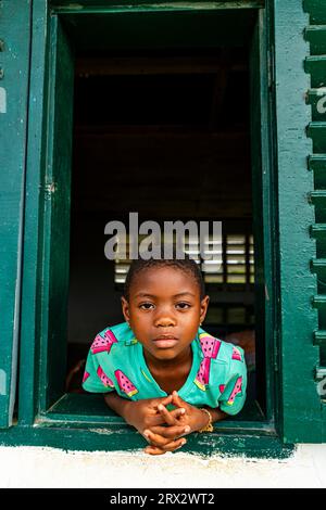 Junge Schulkinder, die aus einem Fenster schauen, Ciudad de la Paz, Rio Muni, Äquatorialguinea, Afrika Stockfoto