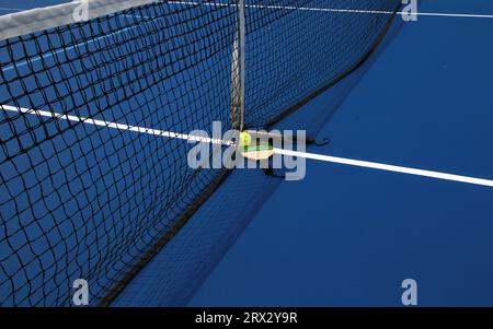 Zwei Pickleball-Paddel mit einem Schlagball am Netz auf einem blauen Pickleball-Platz. Stockfoto