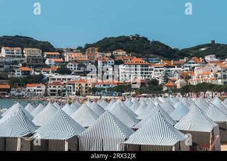 Blick auf grüne Hütten am Strand Sao Martinho do Porto, einem breiten weißen Sandstrand, umgeben von Dünen in einer abgelegenen Bucht, die bei Familien beliebt ist, Oeste, Portugal Stockfoto