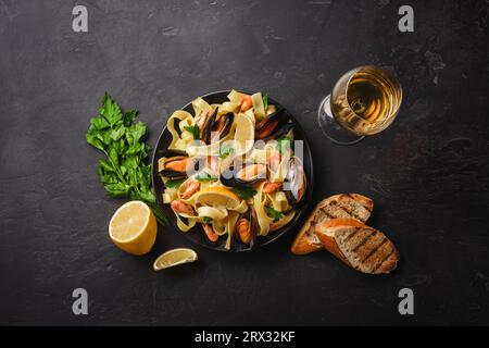 Pasta mit Meeresfrüchten und Weißwein auf steinernen Tisch. Muscheln und Garnelen. Ansicht von oben Stockfoto