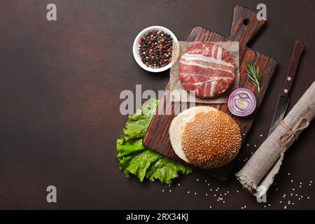 Hamburger Zutaten roh Schnitzel, Salat, Brötchen, Gurken und Zwiebeln auf Rusty Hintergrund. Ansicht von oben mit Platz für Ihren Text. Stockfoto