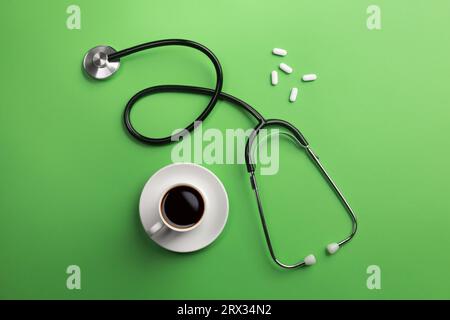 Stethoskop in Ärzte Schreibtisch mit Tasse Kaffee und Pillen. Ansicht von oben. Stockfoto