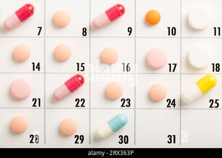 Die Pillen haben eine andere Farbe im Kalender. Medikamente einplanen. Konzentrieren Sie sich auf eine hellgrüne Pille. Hochwertige Fotos Stockfoto