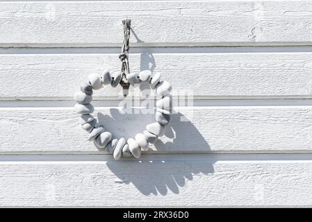 Herzförmige Kette aus weißen Kieseln vor der weißen Holzfassade einer Badehütte am Strand von Skanör med Falsterbo, Skåne, Schweden Stockfoto