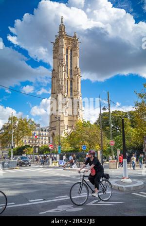 Eine Frau radelt am Tour Saint-Jacques (Saint James Tower) vorbei, einem 52 Meter hohen gotischen Glockenturm im 4. Arrondissement von Paris, Frankreich. Stockfoto