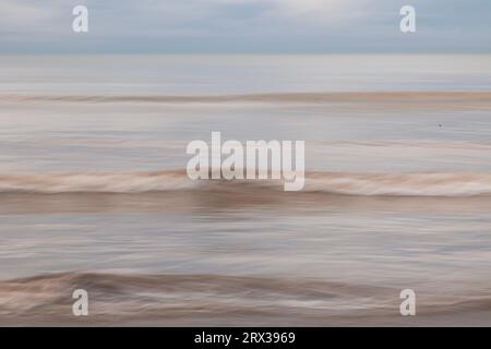 Absichtliche Kamerabewegung von Wellen, die an einem Strand in Worthing, West Sussex, Großbritannien brechen Stockfoto