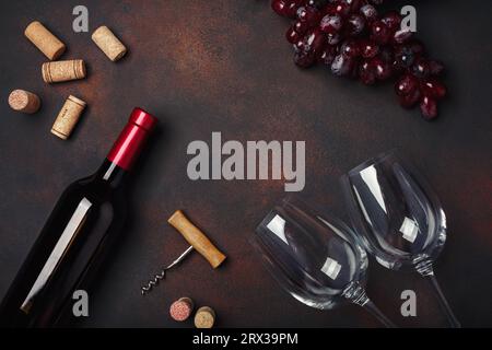 Flasche Wein, zwei Gläser, rote Trauben, Korkenzieher und Korken, auf rostigem Hintergrund Draufsicht, Kopierraum Stockfoto
