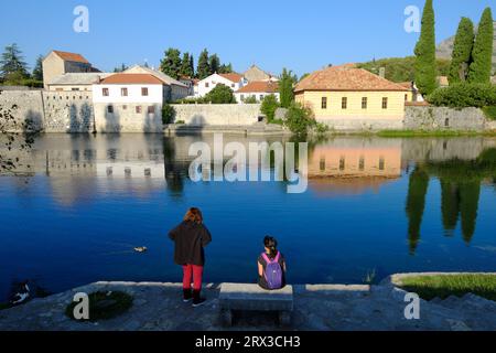Zwei Touristen am Flussufer vor der Altstadt von Trebinje, Bosnien und Herzegowina Stockfoto