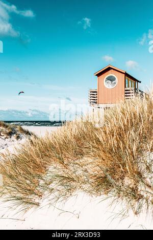 Roter hölzerner Rettungsschwimmer-Aussichtsturm auf Stelzen an der Strandbar in den Sanddünen am Strand Skanör med Falsterbo in der Morgensonne, Skåne, Schweden Stockfoto