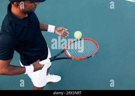 Der hohe Winkel eines nicht erkennbaren Tennisspielers, der einen Ball mit einem Schläger hüpft Stockfoto