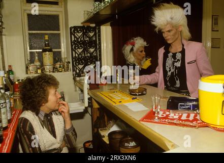 Sigue Sigue Sputnik Bandmitglieder Neal Whitmore aka Neal X und Jane Farrimond bekannt als Yana Yaya an der Bar eines Cherton Hotels. Neal trägt ein Cowboy-T-Shirt, das auf einem Design des schwulen Künstlers Jim French basiert. Die Vermieterin, die überrascht aussieht, serviert die Drinks, bevor sie an diesen Abenden den F1-11-Auftritt von Love Missile im Tiffany’s in der Newbridge Street besucht. Bed and Breakfast Hotelwirtin. Cherton Hotel, Clifton Road, Newcastle upon Tyne, England, 12. März 1986. 1980ER JAHRE UK HOMER SYKES Stockfoto