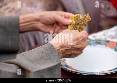 Ein alter Mann, der Thymian und Brot in seinem Haus isst Stockfoto