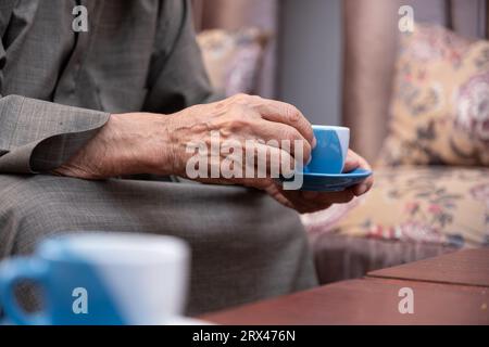 Der alte Mann trinkt Kaffee mit einem Lächeln im Gesicht Stockfoto