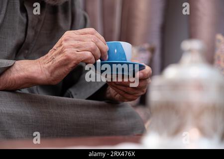 Der alte Mann trinkt Kaffee mit einem Lächeln im Gesicht Stockfoto