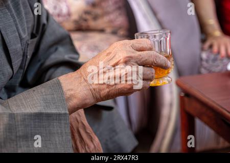 Arabischer alter Mann trinkt Tee und hält ein Glas Tee in der Hand Stockfoto