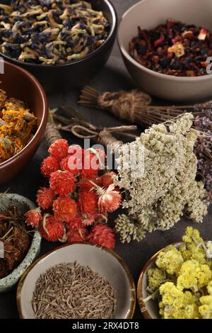 Viele verschiedene trockene Kräuter und Blumen auf dunkelgrauem Tisch Stockfoto