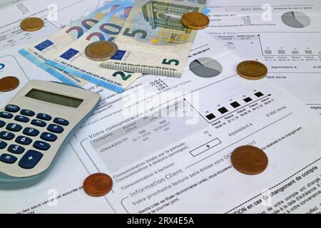 Ein Rechner und einige Euro-Münzen und Banknoten auf einer französischen Wasserrechnung. Stockfoto