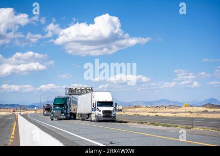 Industrielle lange Transporteure große Sattelzugmaschinen mit verschiedenen Aufliegern machen eine Pause für Lkw-Fahrer, die auf der Straße stehen Stockfoto