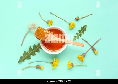 Schüssel mit leckerem Honig, Wabenwabe und Löwenzahnblüten auf türkisfarbenem Hintergrund Stockfoto