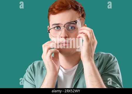 Ängstlicher junger Mann in Brille auf grünem Hintergrund, Nahaufnahme Stockfoto