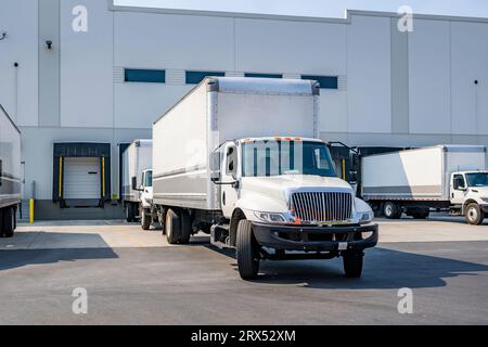 Mittelschwerer, weißer Day Cab-Auflieger nach Industriestandard mit langem Kastenanhänger für lokale Lieferungen und kleine Unternehmen, die auf der Wareh stehen Stockfoto