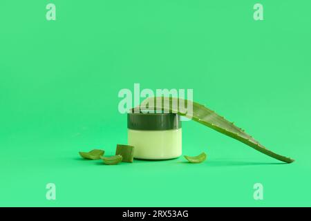 Glas kosmetische Creme mit Aloe Vera-Blättern auf grünem Hintergrund Stockfoto