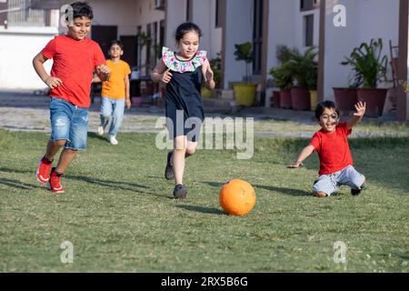 Gruppe glücklicher indischer Kinder, die Fußball oder Fußball im Sommerpark spielen. Stockfoto