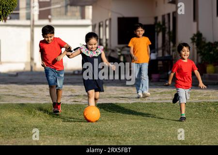 Gruppe glücklicher indischer Kinder, die Fußball oder Fußball im Sommerpark spielen. Stockfoto