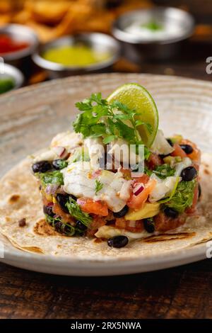 Fisch-Ceviche-Toast auf Porzellanplatte auf Holztisch. Spanischer Name: Tostada ceviche de pescado Stockfoto