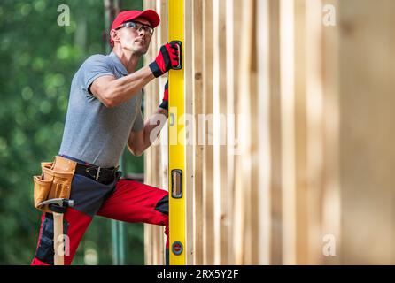 Bauarbeiter mit Wasserwagenprüfung auf vertikalen hölzernen Gerüstebenen Stockfoto