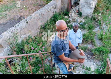 Glücklicher Bauarbeiter, der einen Laptop mit einem älteren Mann vor Ort hält Stockfoto