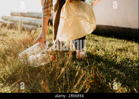 Junge, der Plastikflaschen auf Gras aufnimmt Stockfoto