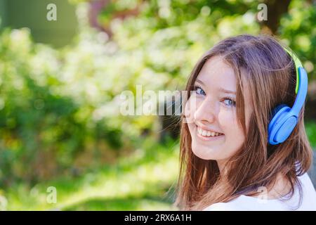 Lächelndes Mädchen im Teenageralter, das Musik über kabellose Kopfhörer hört Stockfoto