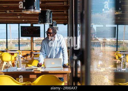 Glücklicher leitender Ingenieur, der am Tisch im Restaurant arbeitet Stockfoto