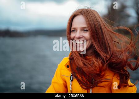 Glückliche rothaarige Frau mit gelber Jacke Stockfoto