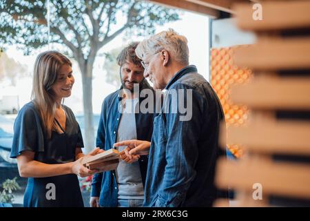 Glückliche Geschäftsfrau zeigt Geschäftsleuten im Büro Designmodell Stockfoto