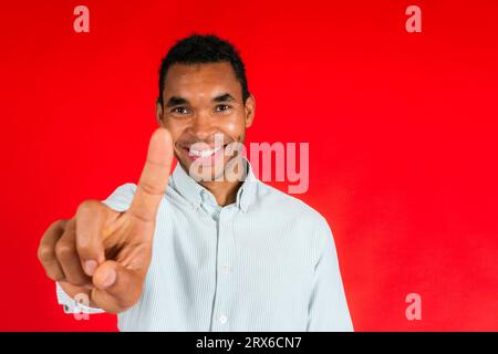 Lächelnder Mann mit Zeigefinger vor rotem Hintergrund Stockfoto