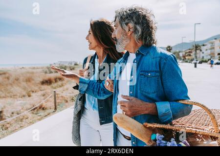 Älterer Mann mit Picknickkorb, der mit einer Frau in Strandnähe spricht Stockfoto