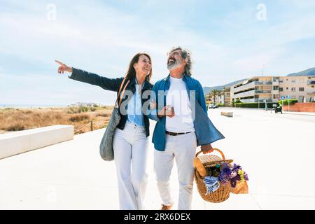 Glückliche ältere Frau zeigt und Mann lacht beim Spaziergang auf dem Fußweg Stockfoto