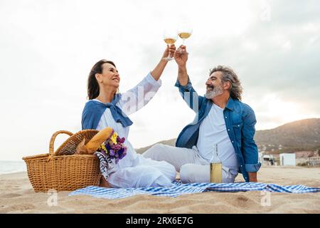 Glückliches Seniorenpaar, das am Strand auf Weinglas anstoßen möchte Stockfoto