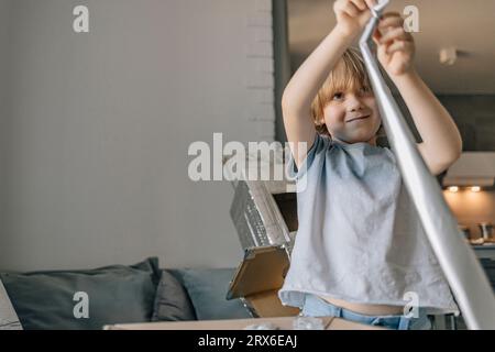 Junge mit Folienpapier, der zu Hause handgefertigten Astronautenanzug macht Stockfoto