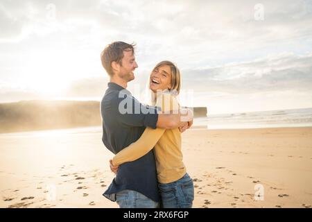 Glückliches Paar, das sich umarmt und den Urlaub am Strand genießt Stockfoto