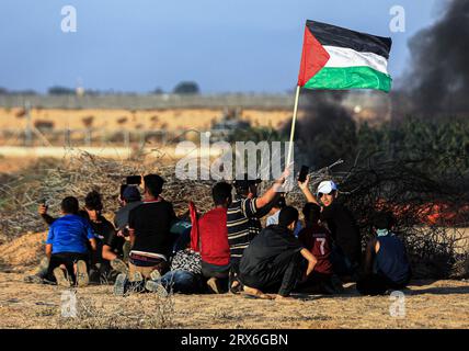 Gaza, Palästina. September 2023. Die Demonstranten verstecken sich, während sie eine palästinensische Flagge bei den Konfrontationen mit israelischen Sicherheitskräften entlang der Grenze zu Israel, östlich von Khan Yunis, südlich des Gazastreifens, halten. Quelle: SOPA Images Limited/Alamy Live News Stockfoto