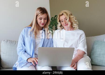 Lächelnde Frau, die der Mutter hilft, den Laptop zu benutzen Stockfoto